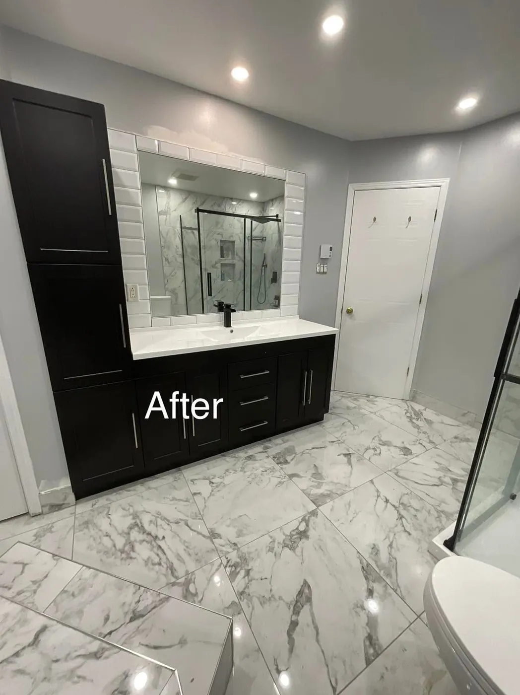 Dark vanity with a beveled white tile mirror frame and marble look floor