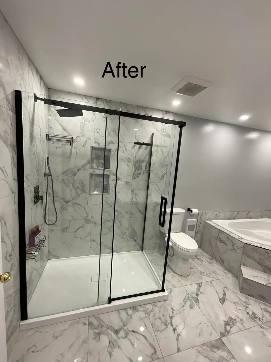 The same space with a frameless black shower, marble look walls and floor